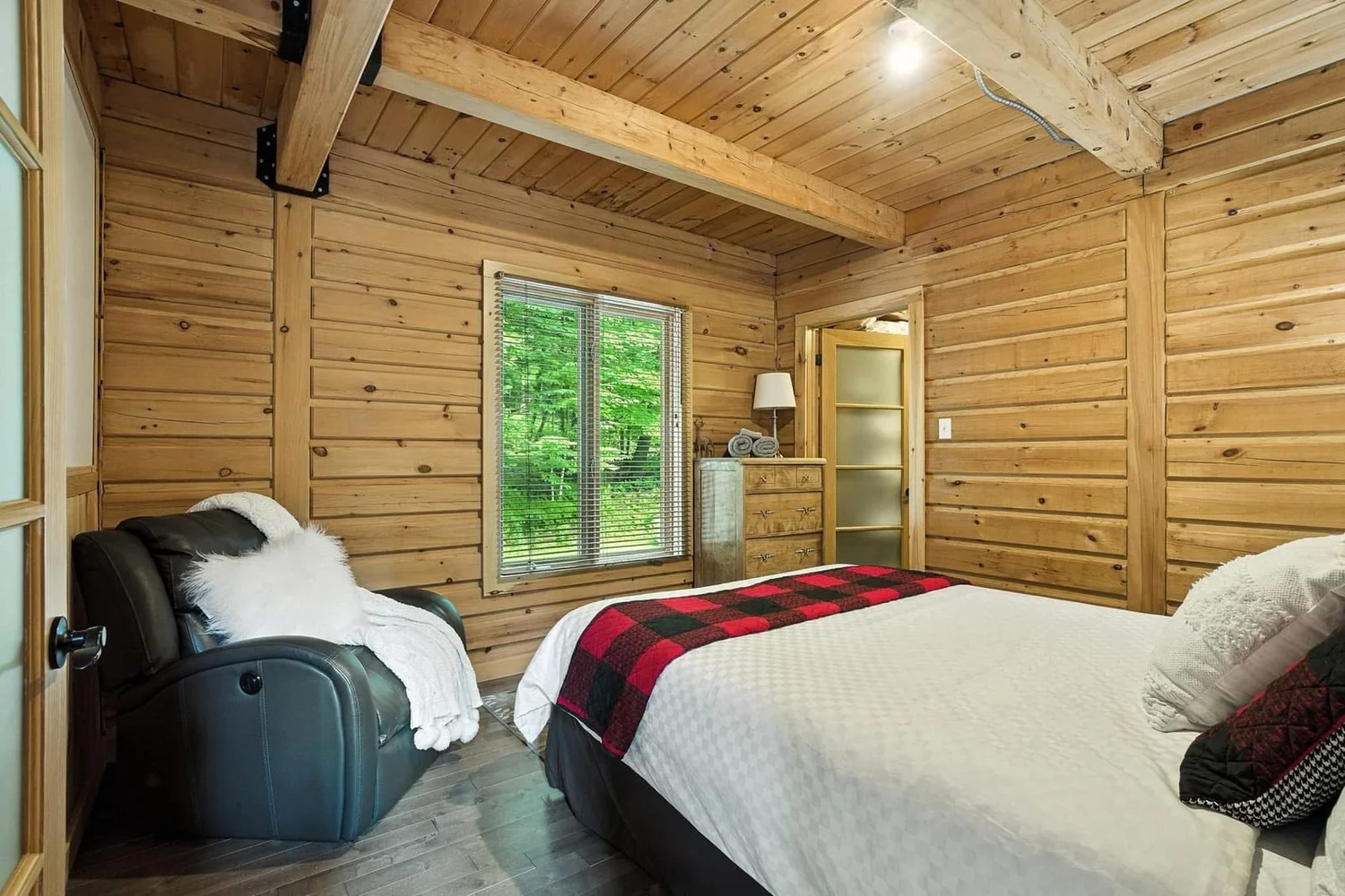 Chambre en bois avec grand lit et fenêtres sur la forêt