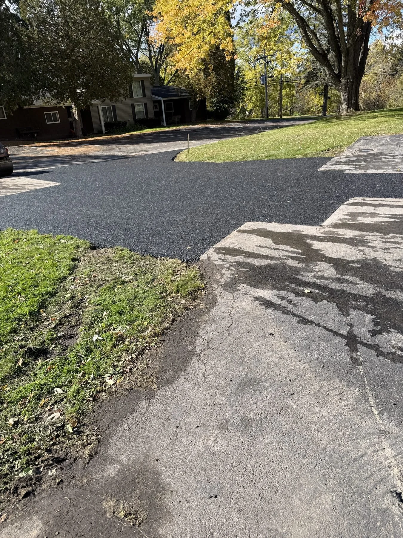 Large asphalt repair curving around a lawn