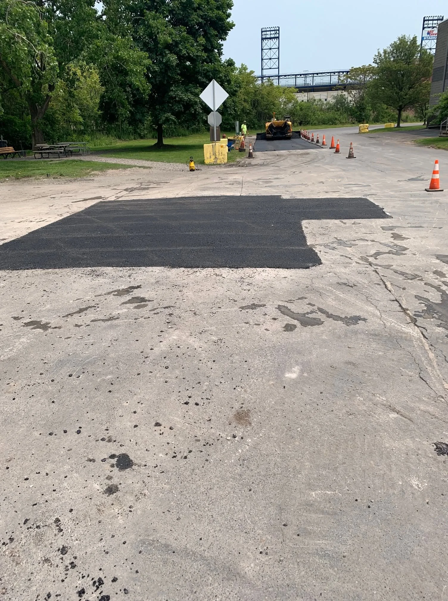 Large asphalt patch with paving crew in the background