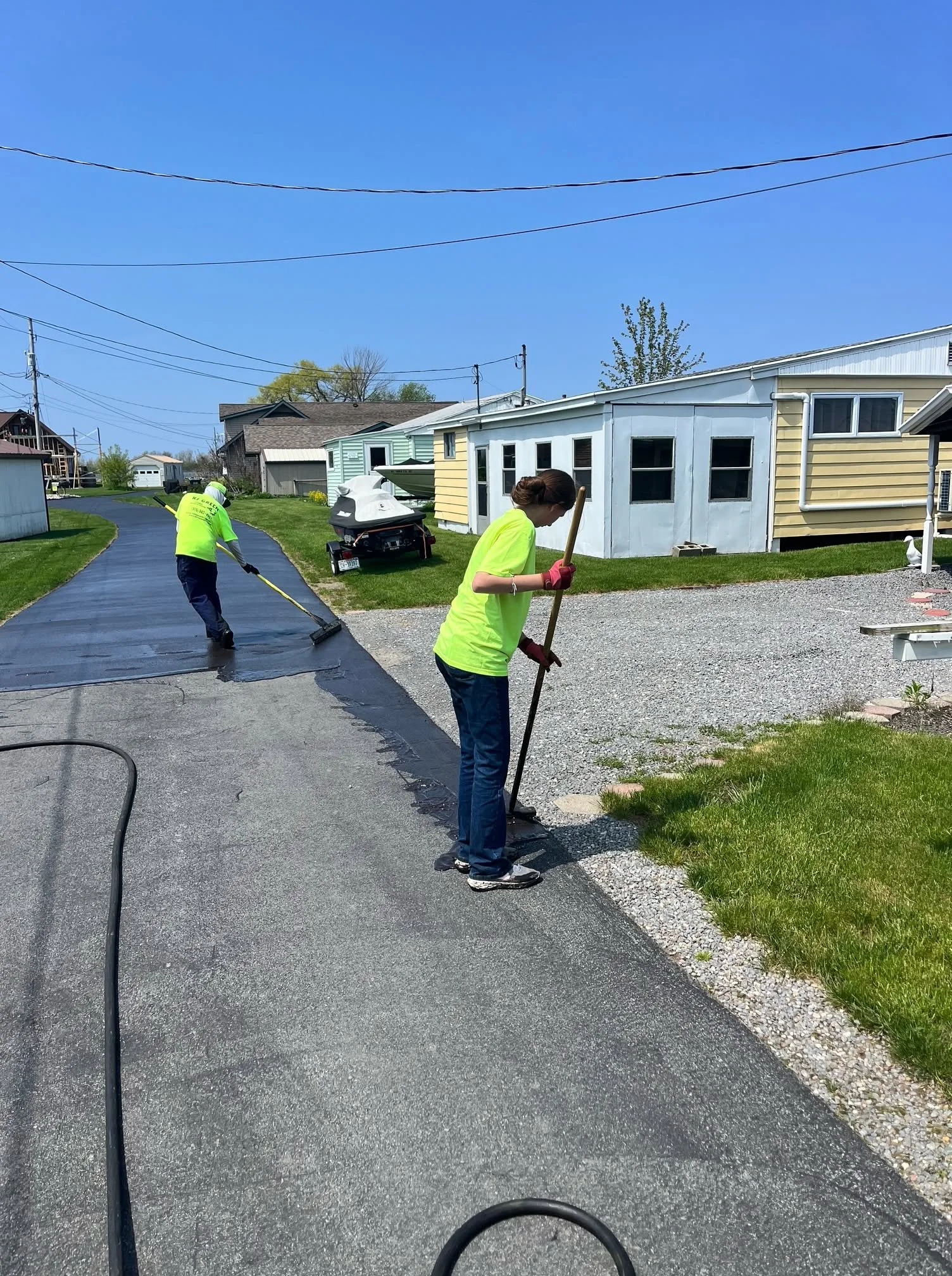 RJ Green crew broom-applying sealcoat to a driveway