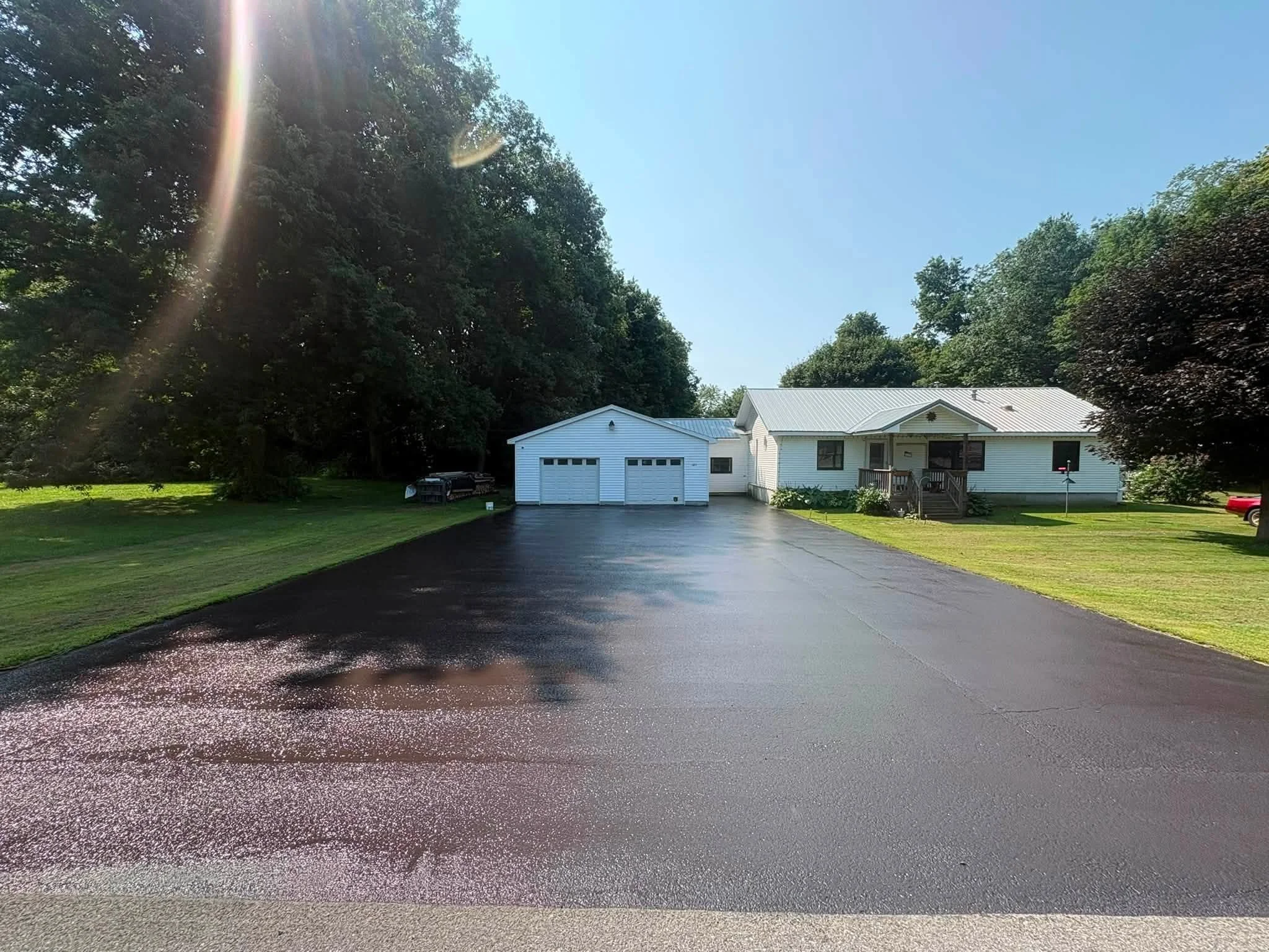 Sealcoated driveway leading to a white two-car garage