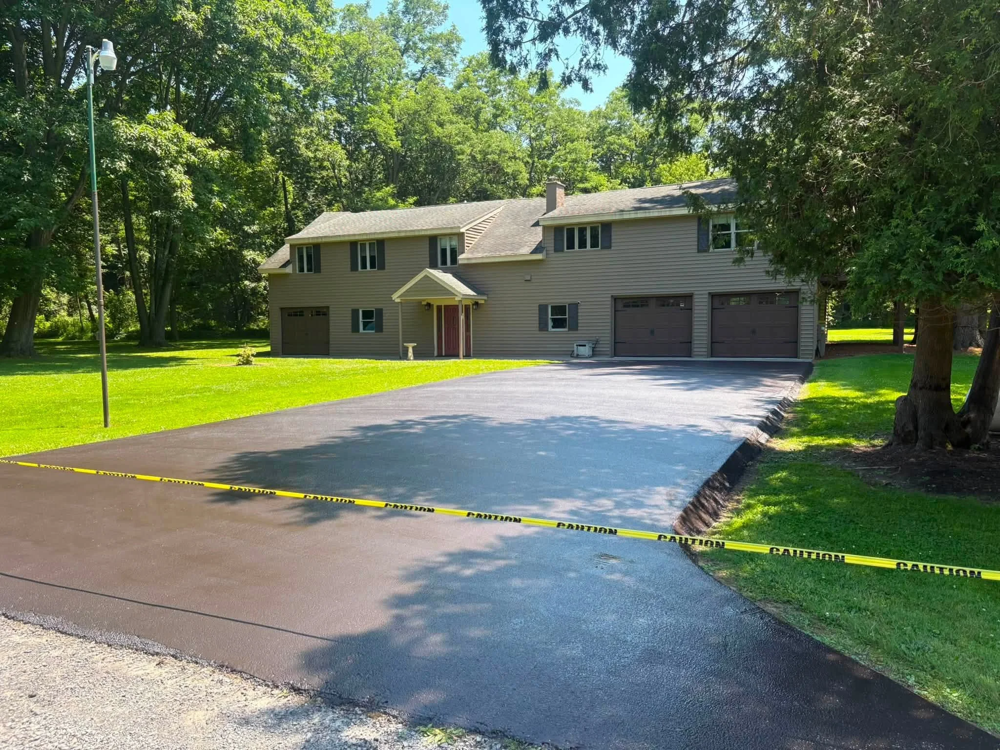 Wide sealcoated driveway in front of a two-story home