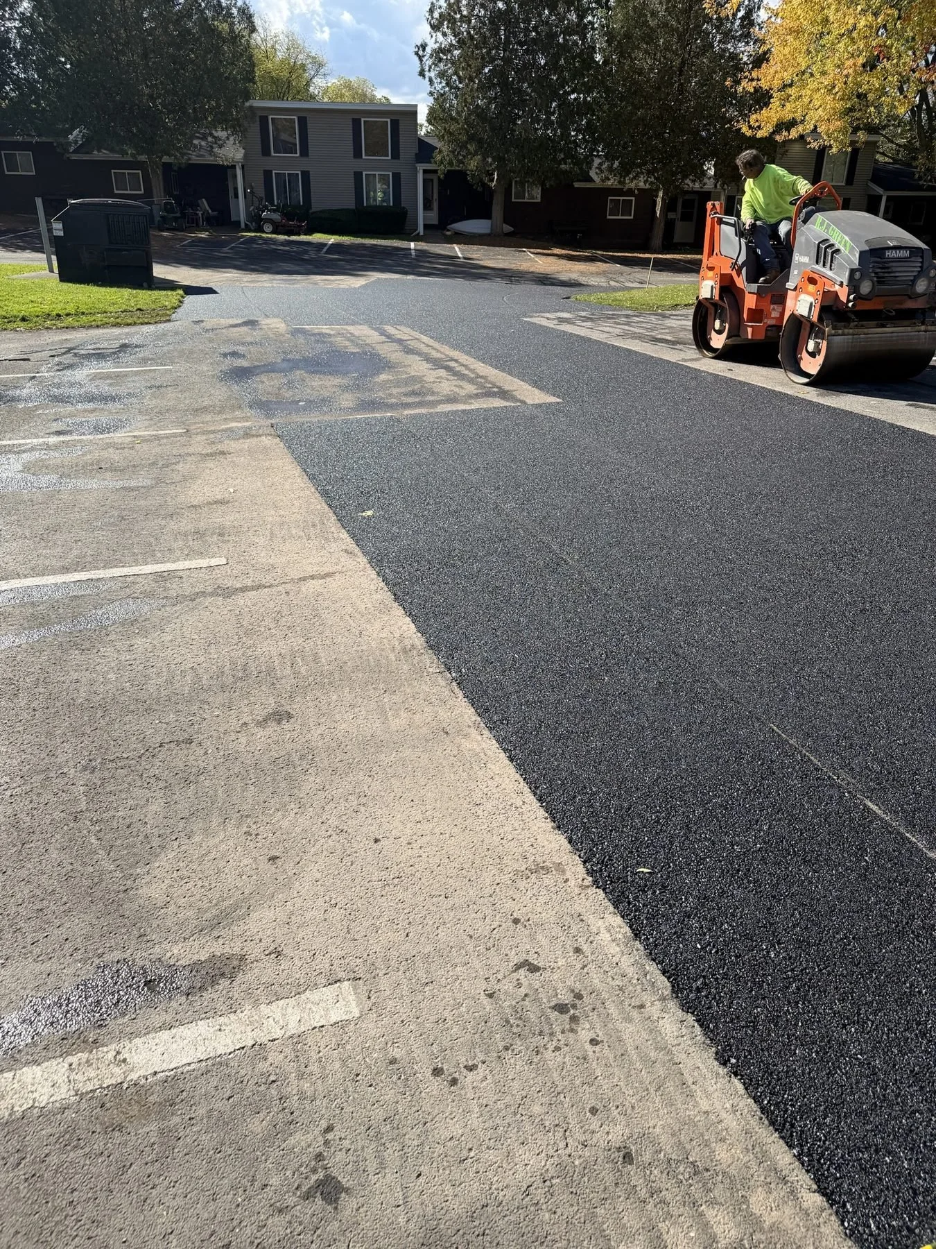 RJ Green crew rolling a large asphalt repair in a parking lot