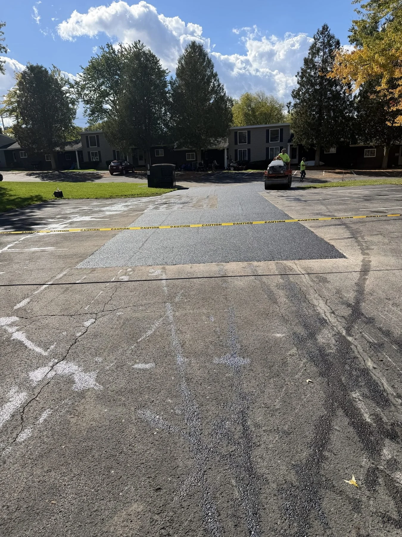 Large section of new asphalt being rolled in an apartment complex lot