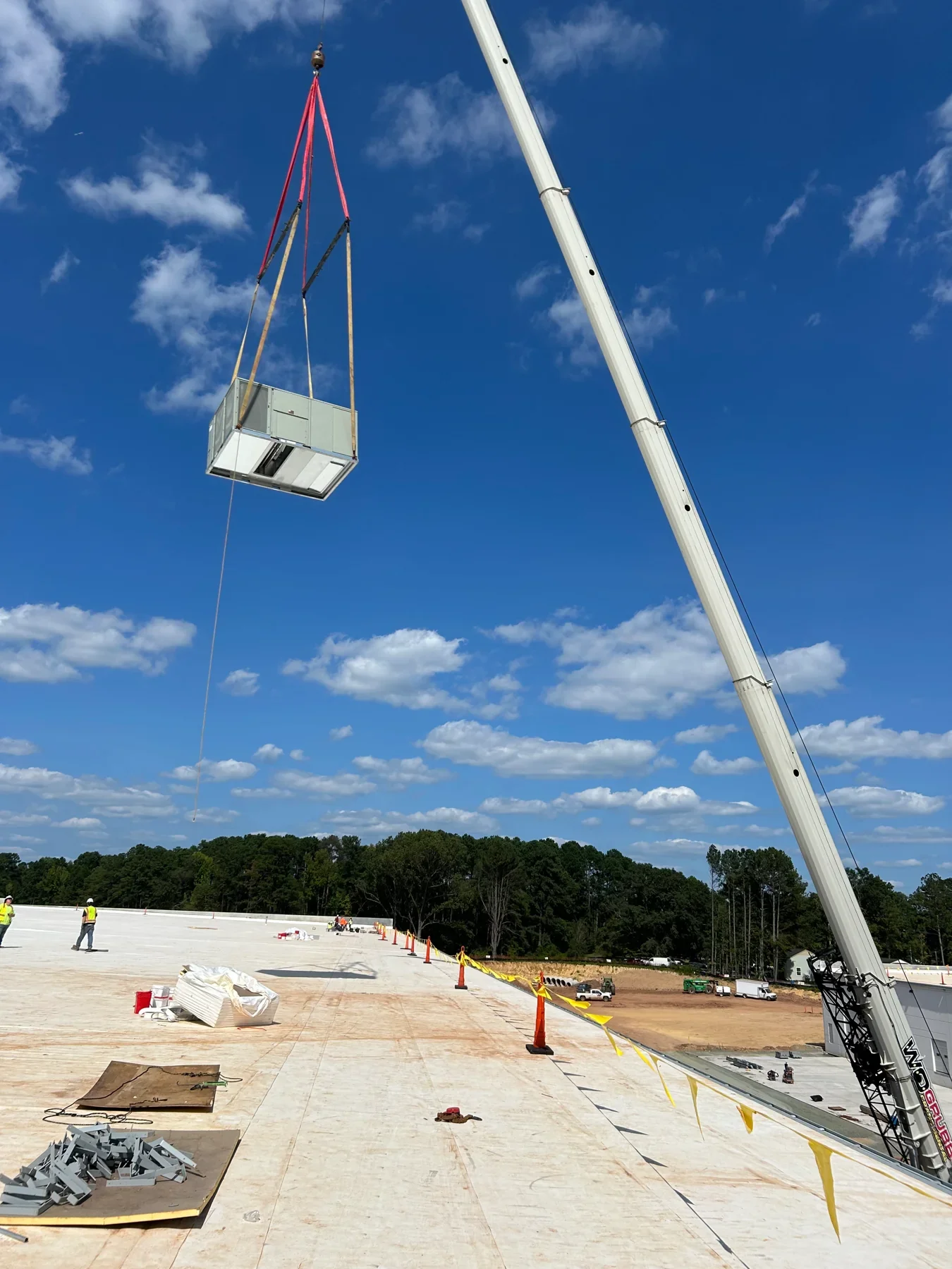 Crane lifting HVAC equipment to a rooftop