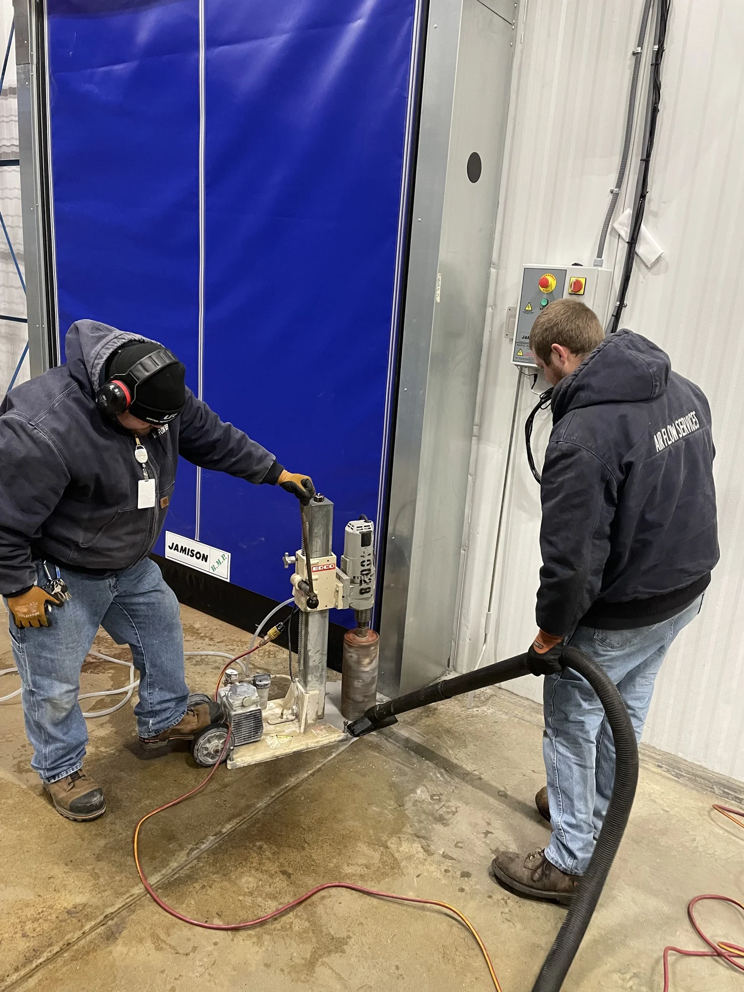 Two technicians working on refrigeration equipment beside a cold-room door