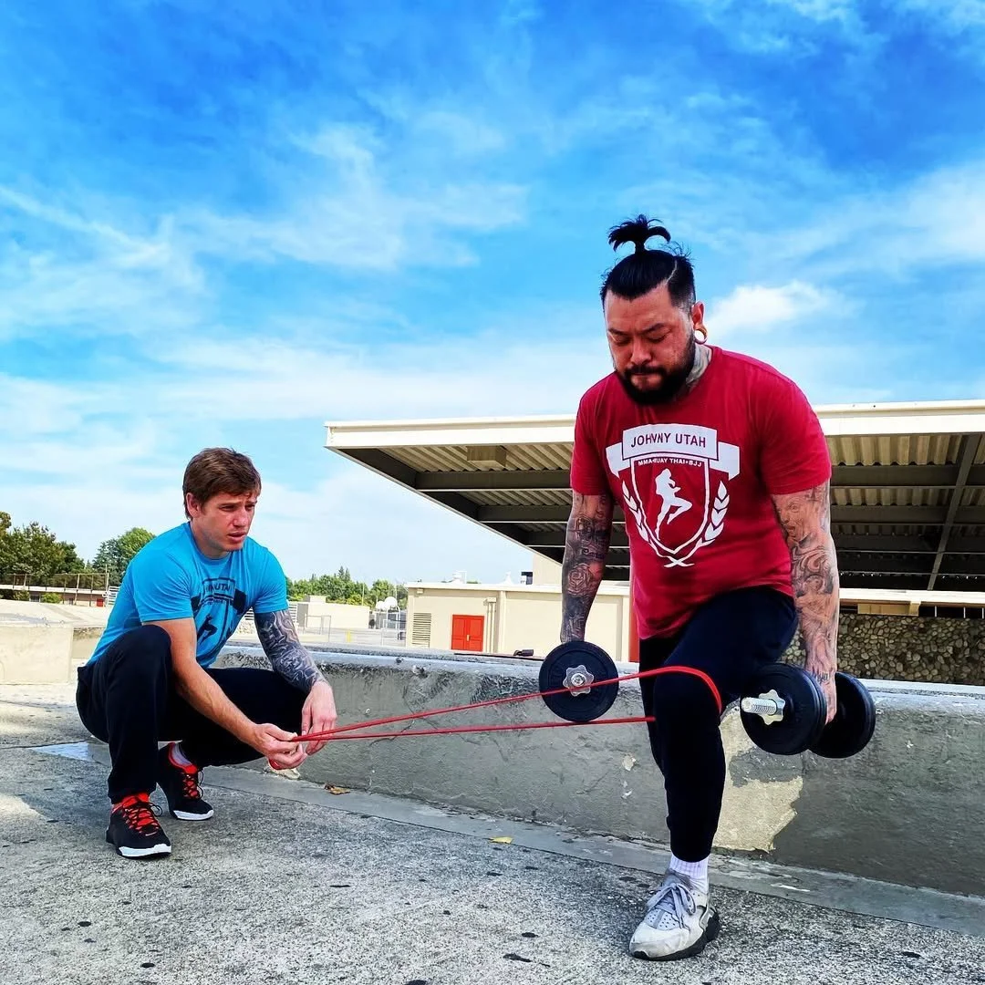 Daniel coaching a band-resisted dumbbell lunge outdoors