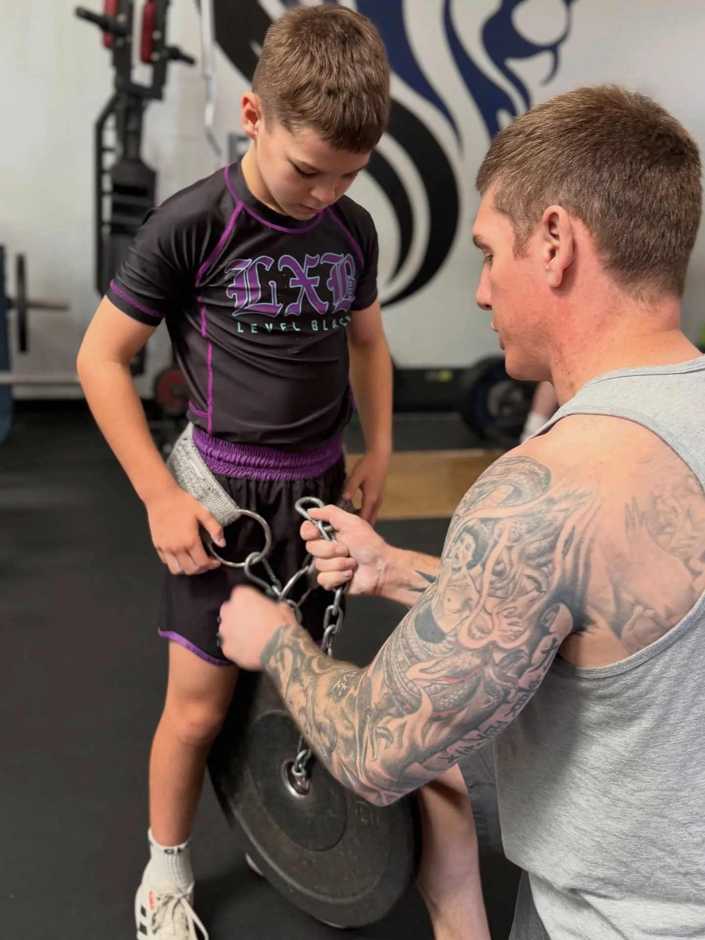 Daniel helping a young athlete adjust a weight belt