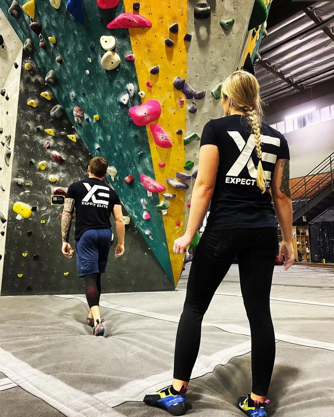 Daniel and Jana at an indoor climbing wall in Expect Elite shirts