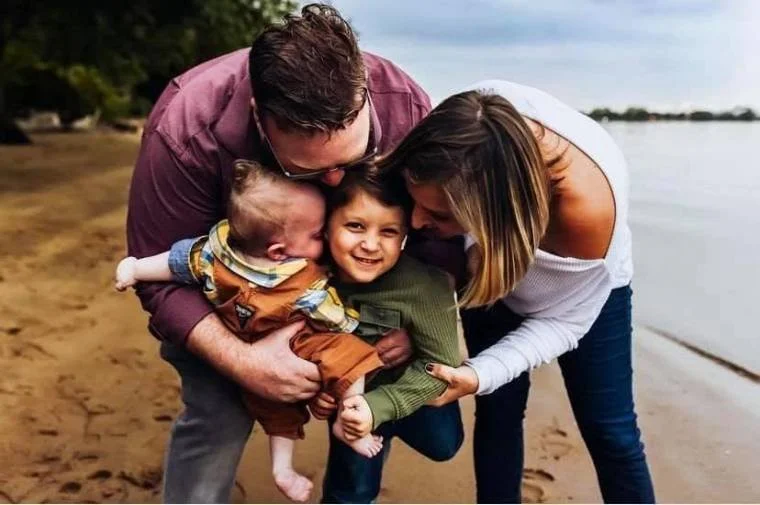 Bryan and Danielle hugging Liam and Ethan on the beach