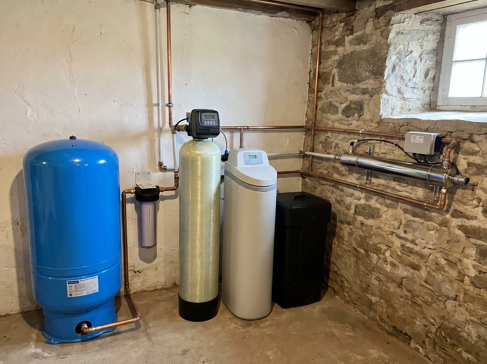 Well water treatment system with sediment filter, iron filter, softener and UV next to a well pressure tank