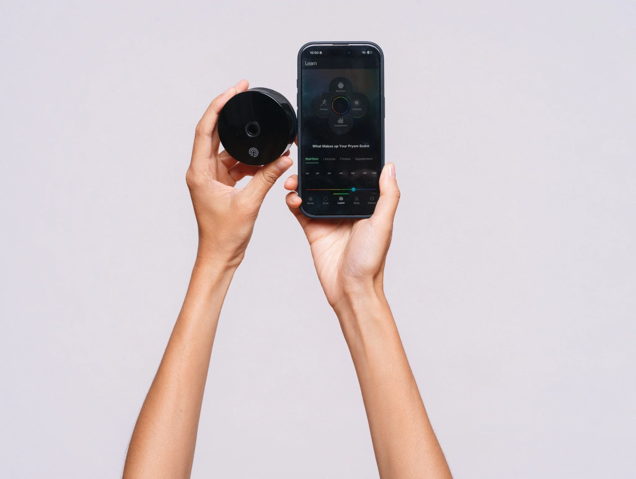 Hands holding a Prysm iO scanner and phone displaying the Prysm app