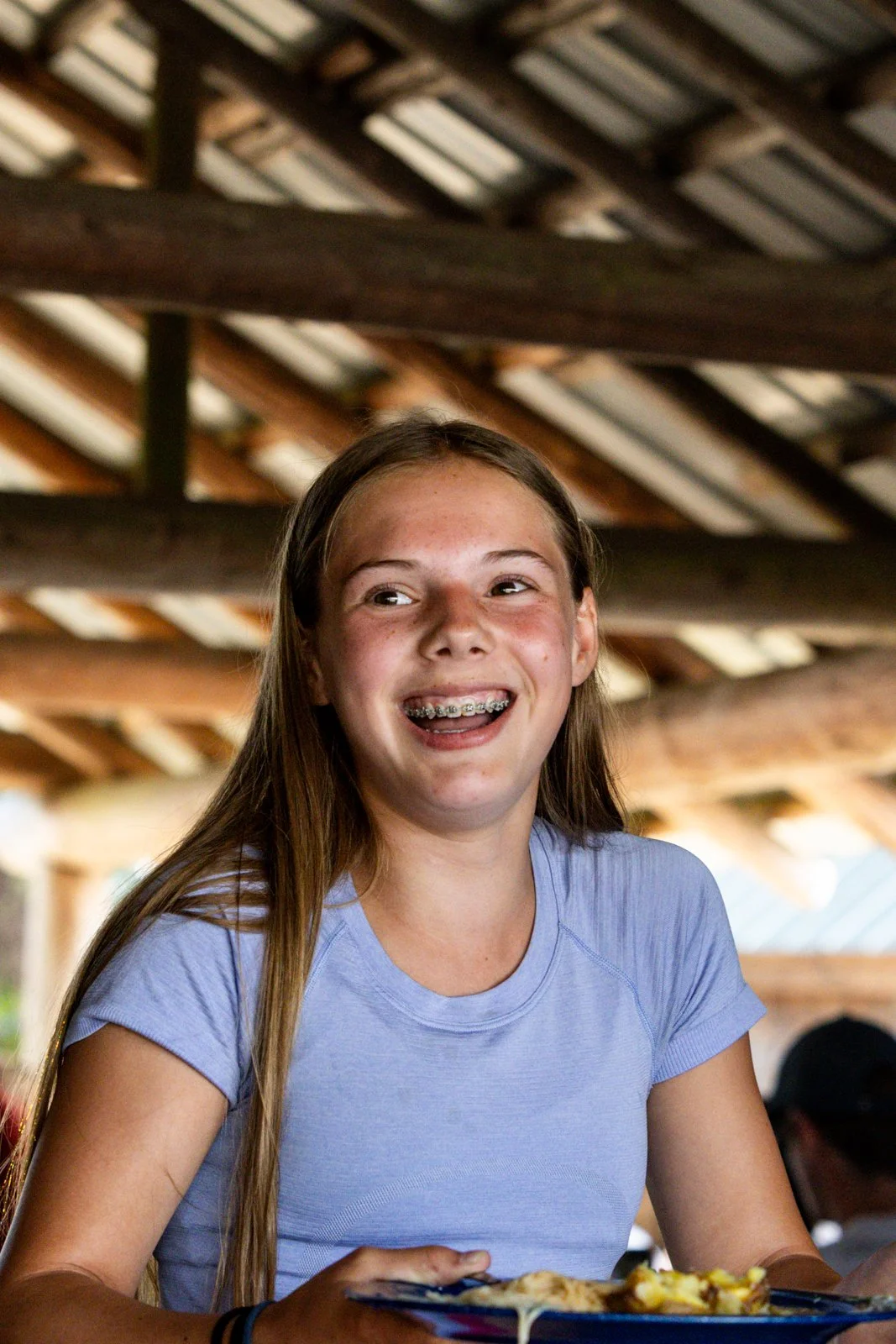 A camper laughing at a meal in the dining hall