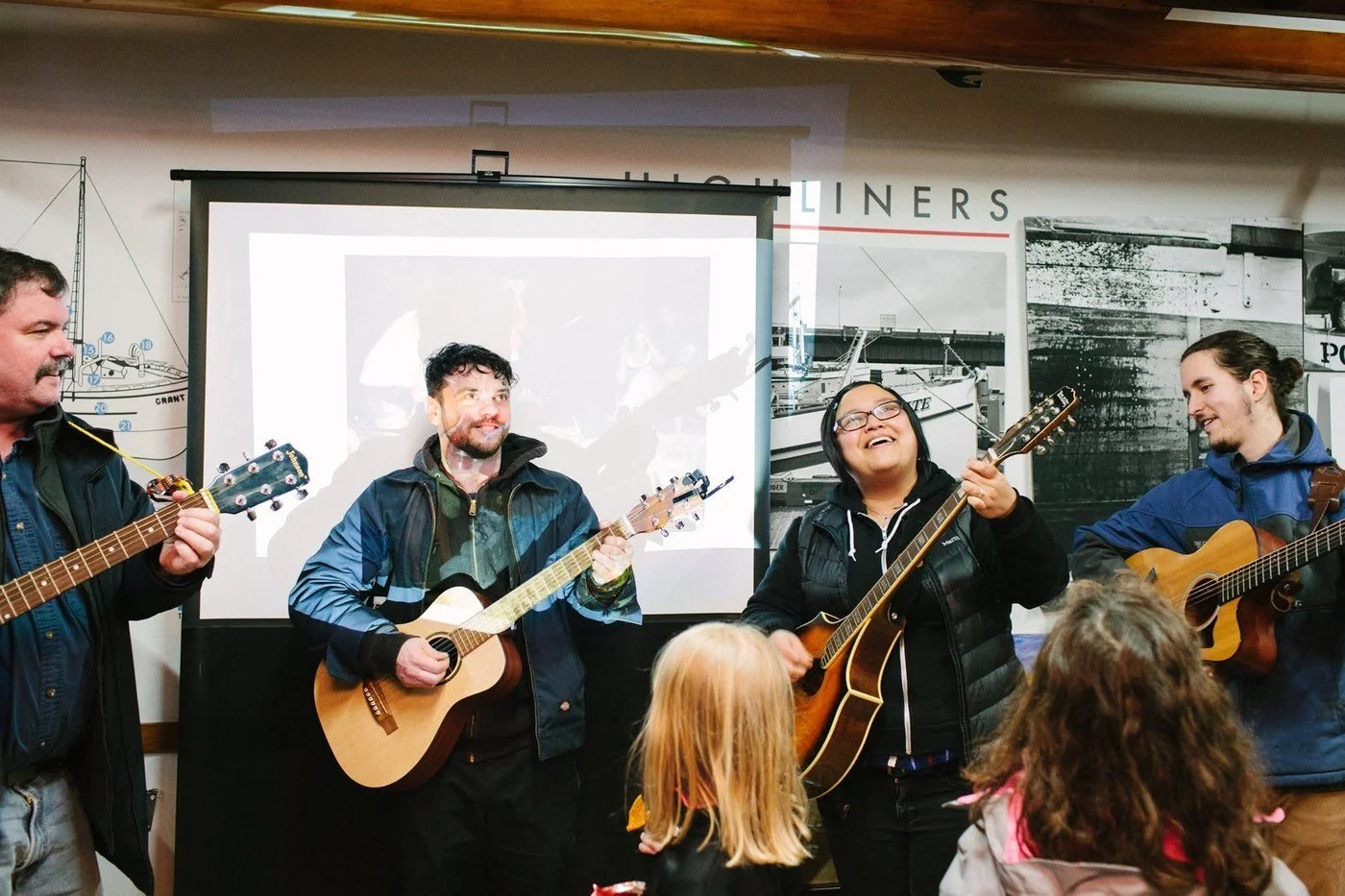 Four people playing guitars and singing at the kickoff event