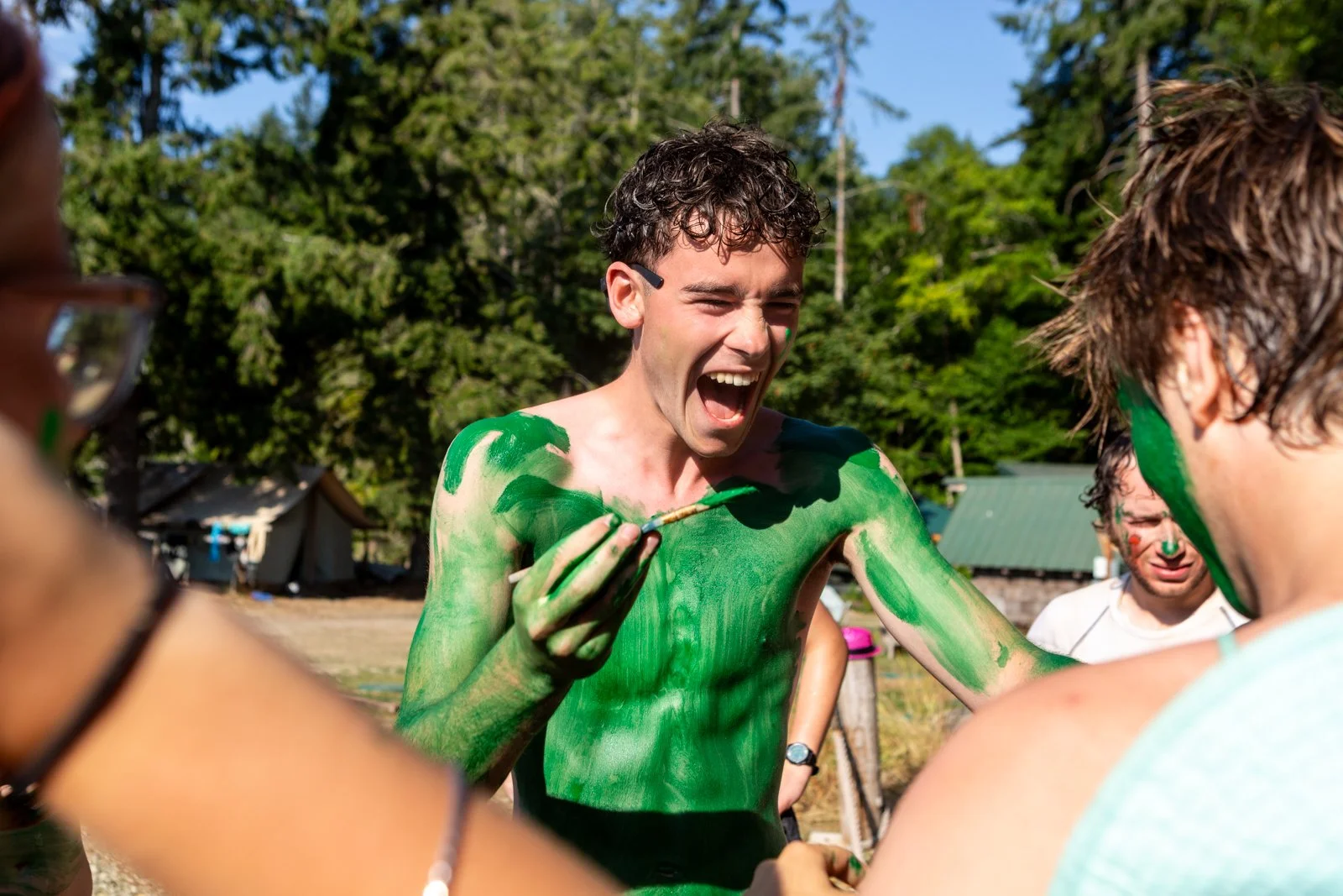 A camper covered in green paint laughing with friends