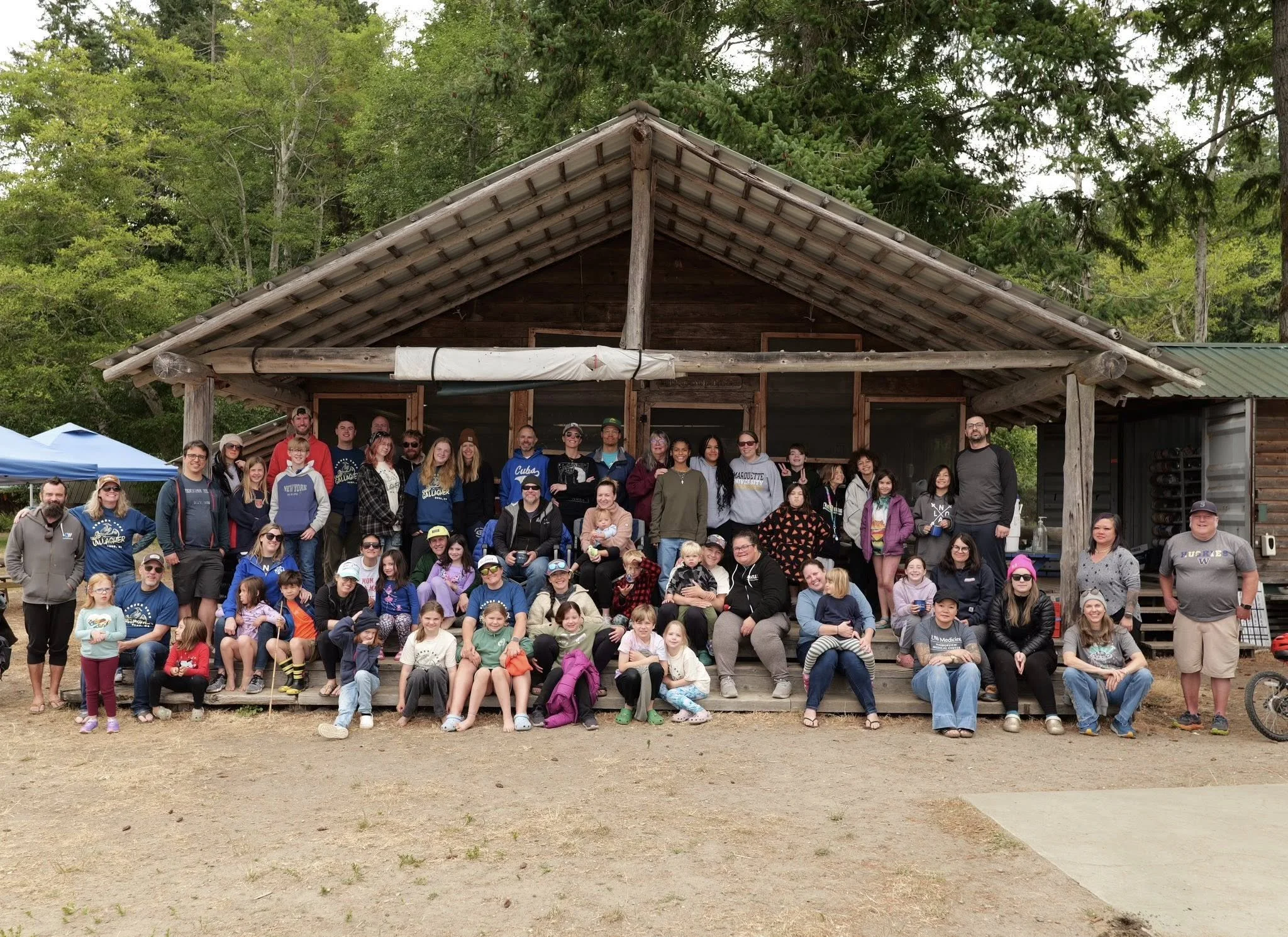 A large family camp group gathered in front of a Camp building