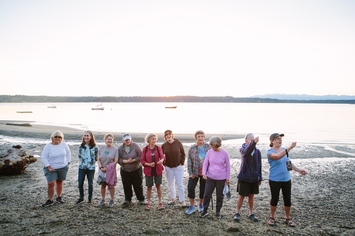 A row of adults standing together on the beach