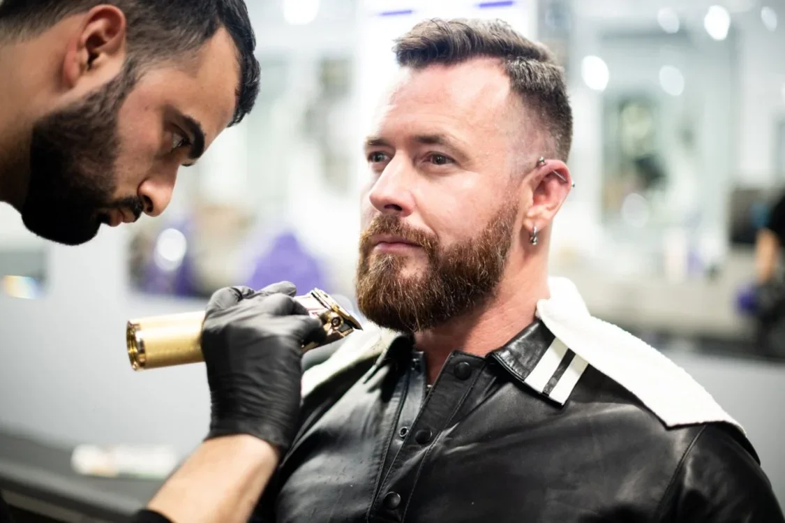 Barber shaping a client’s beard with clippers at TRIMMED