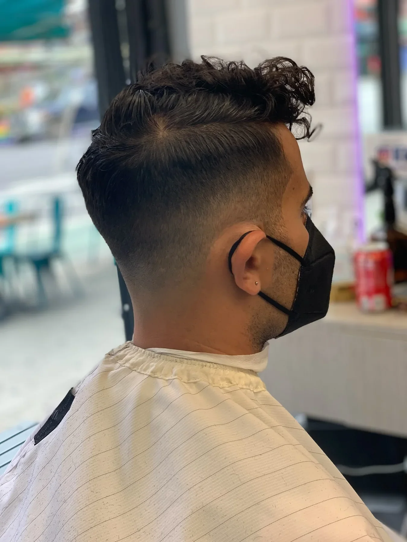 Curly top with a tapered skin fade, viewed from the side