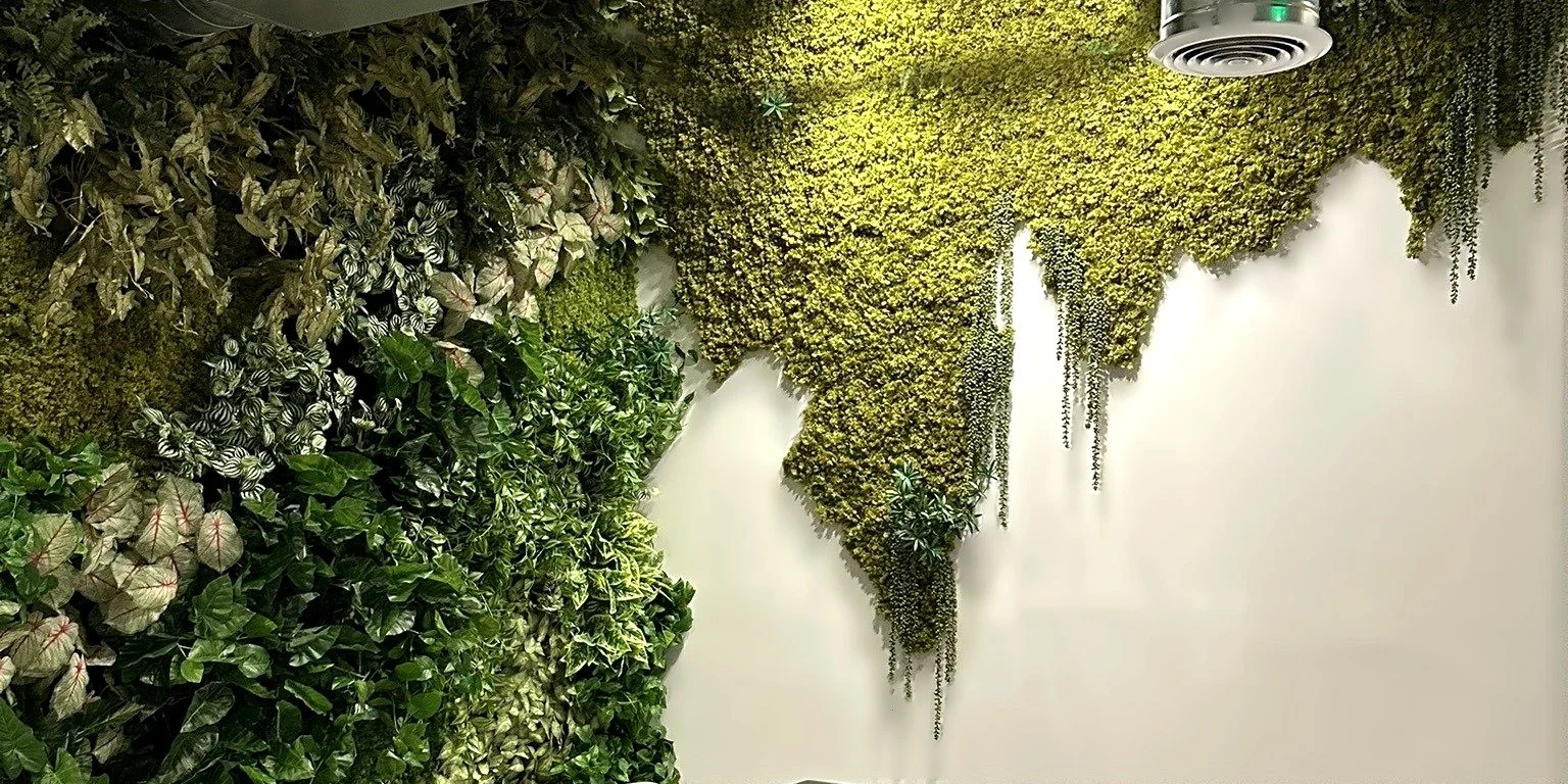 A greenwall that breaks into a moss world map across a coworking office wall in Brickell, Miami
