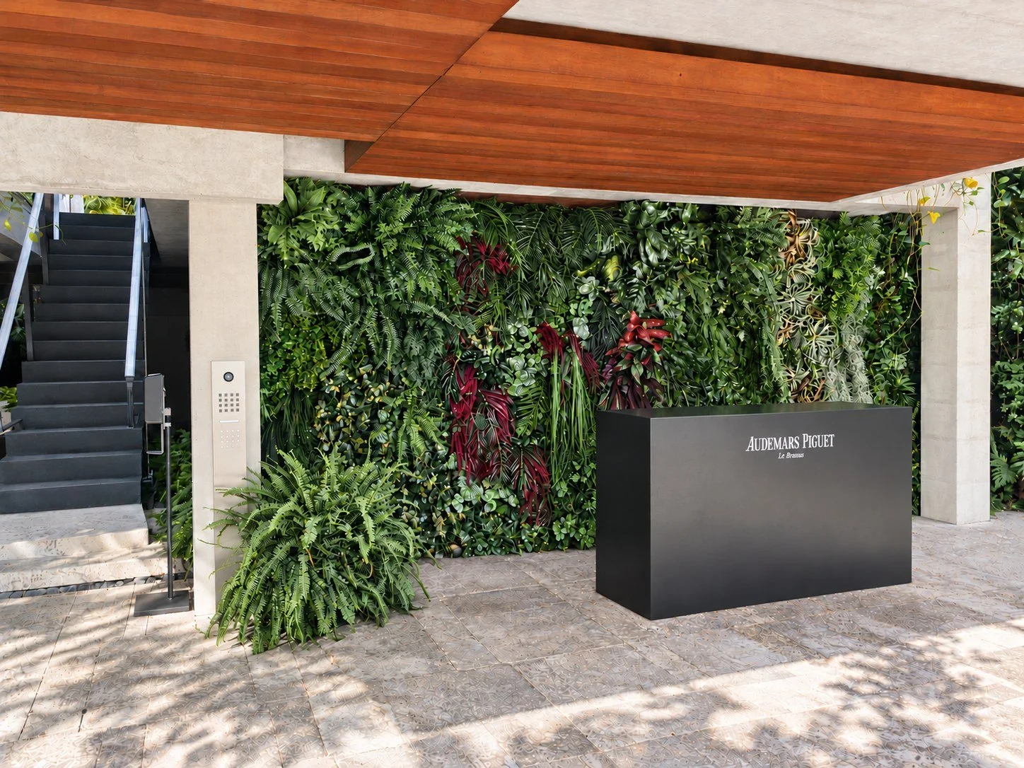 Limited UV greenwall with ferns and red tropical accents beneath a covered wood-ceilinged entry in Miami Beach, FL
