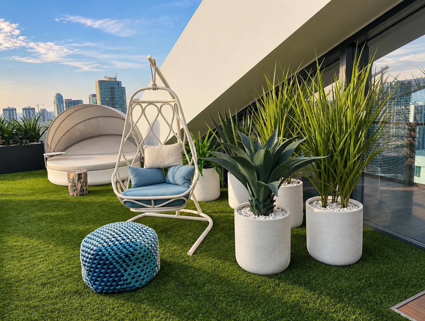 Agave and ornamental grasses in textured white planters with white stone top dressing on a Miami penthouse terrace overlooking the skyline