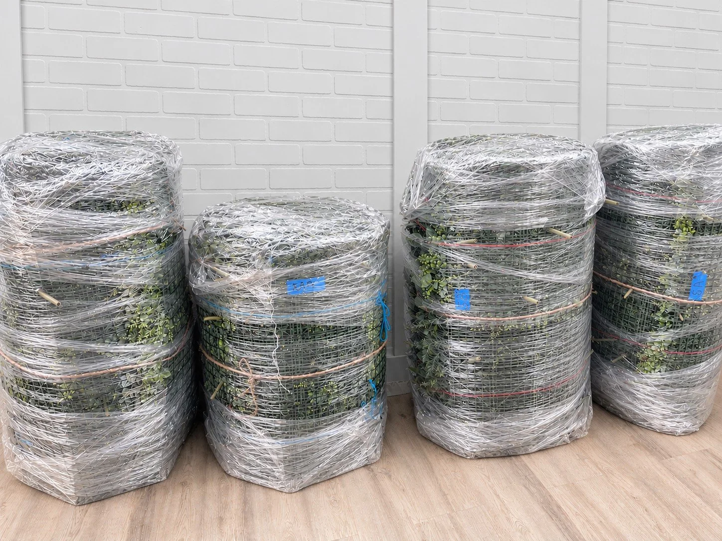 Finished greenwall panels rolled, wrapped, tied, and labeled in the Lush Artificial Greenwalls Miami studio, ready to ship