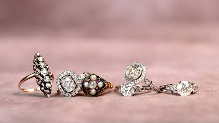 Collection of vintage diamond and gemstone rings on pink fabric