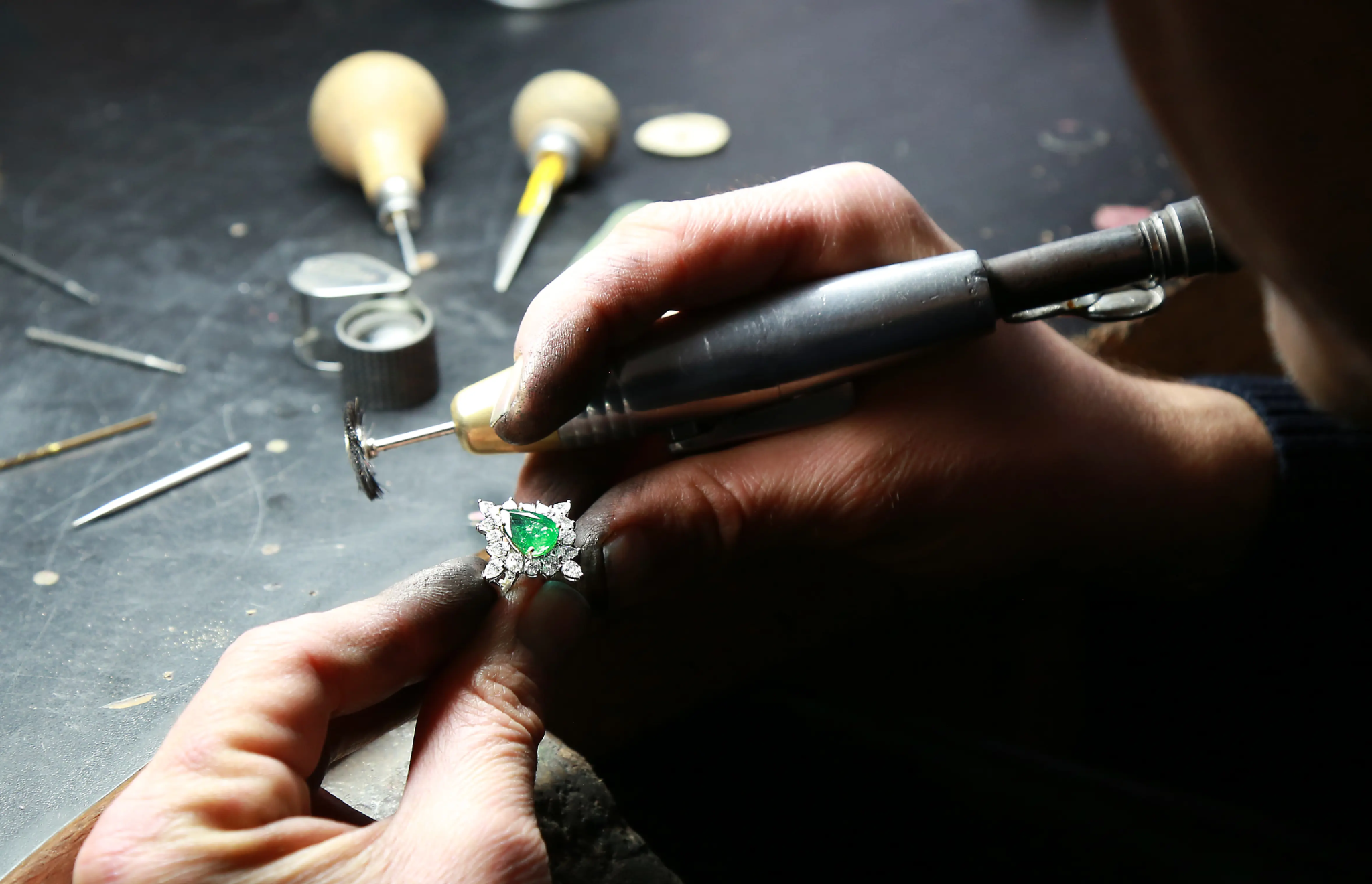 Jeweler working on a green gemstone and diamond ring at the workbench