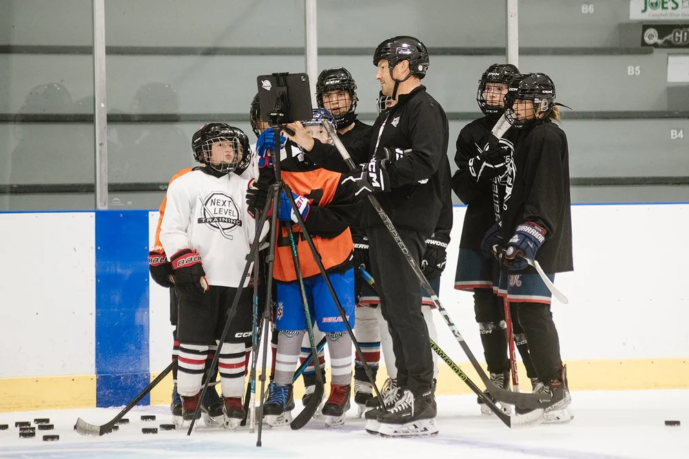 Bryce showing players video on a tablet during an on-ice session