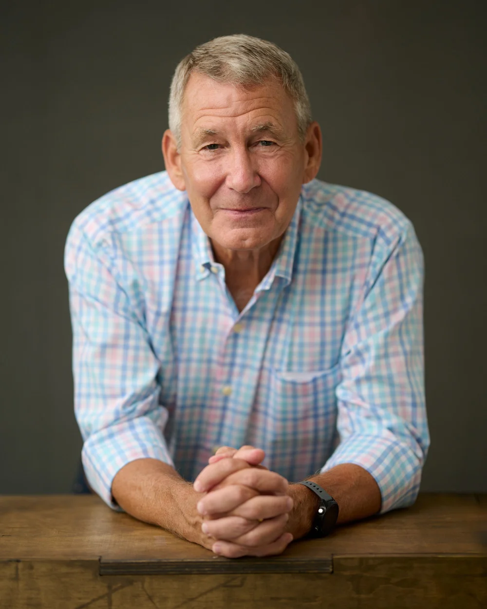 Portrait of a man in a checked shirt leaning on a wooden table
