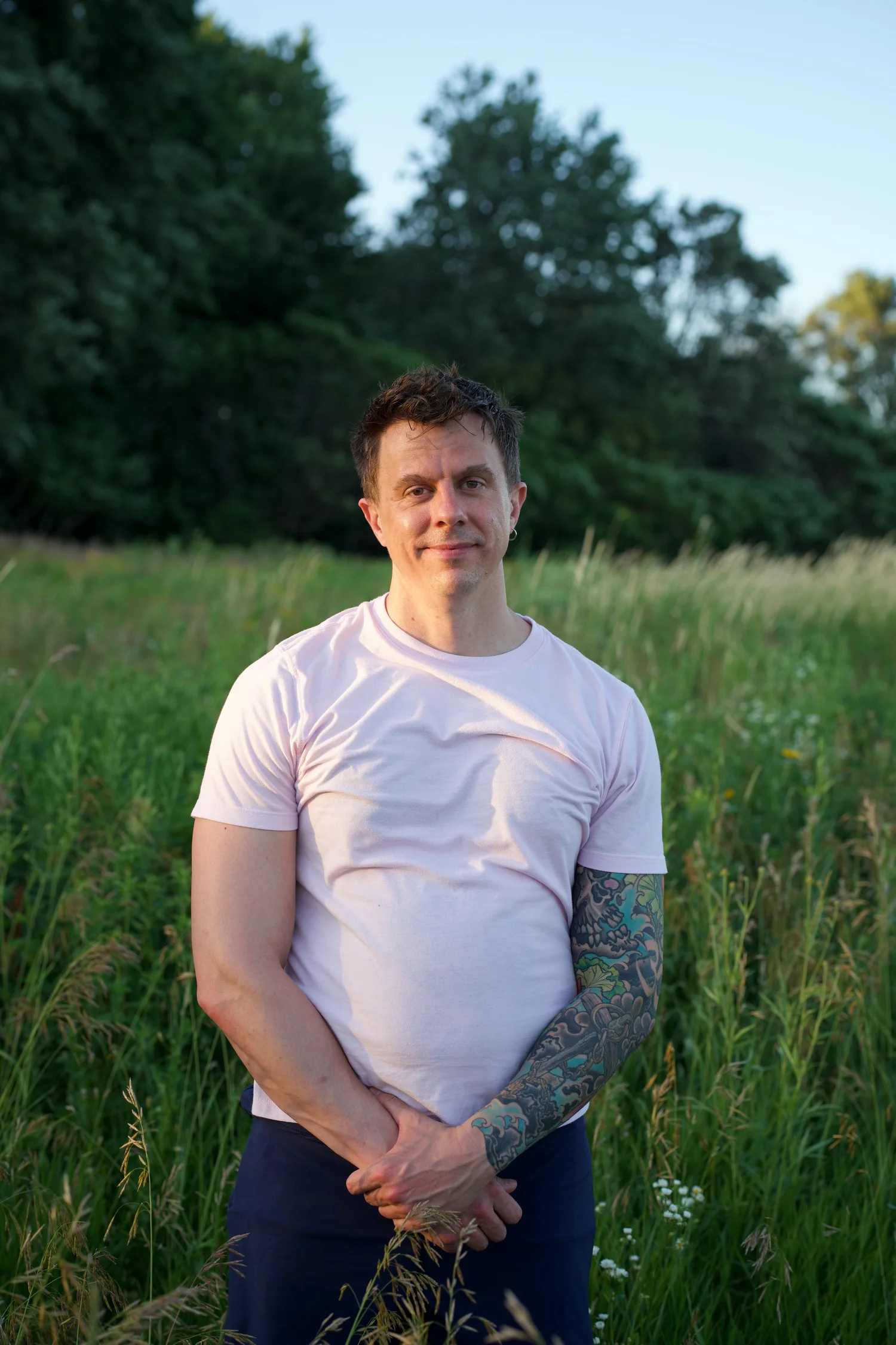 Looking toward the camera with hands clasped above the grass.