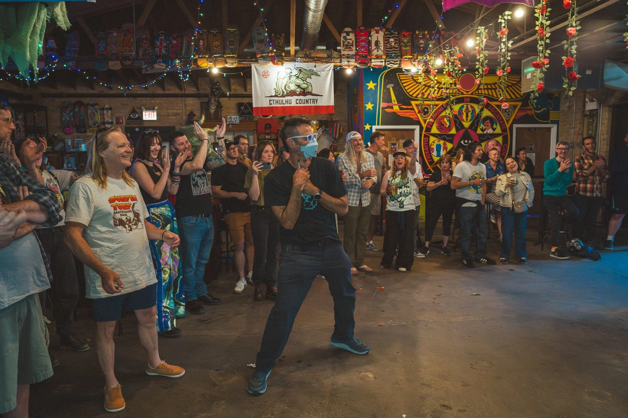A vocalist stands in the middle of an open floor, surrounded by an audience.