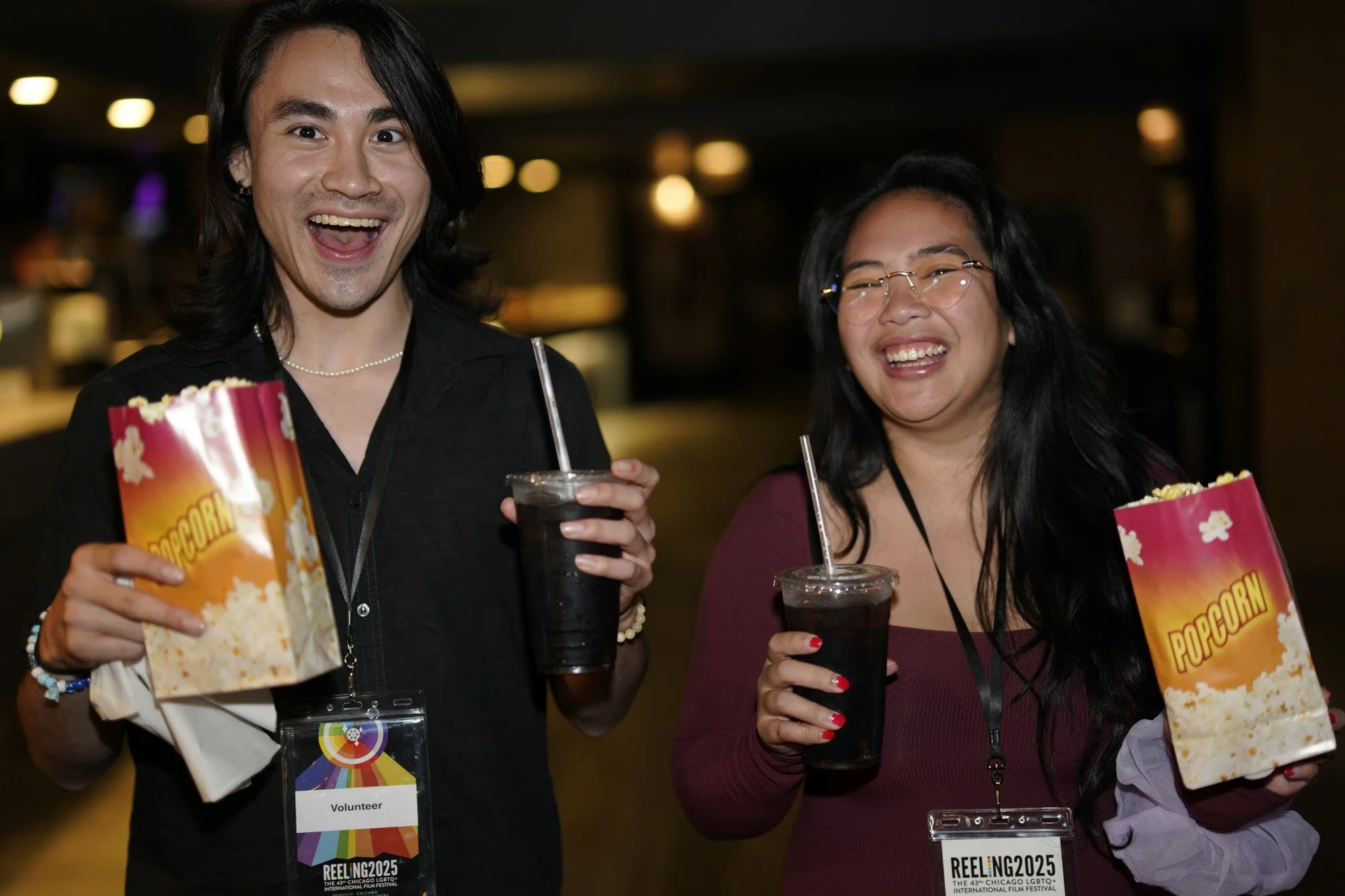 Two smiling festival attendees hold popcorn and drinks inside the cinema.