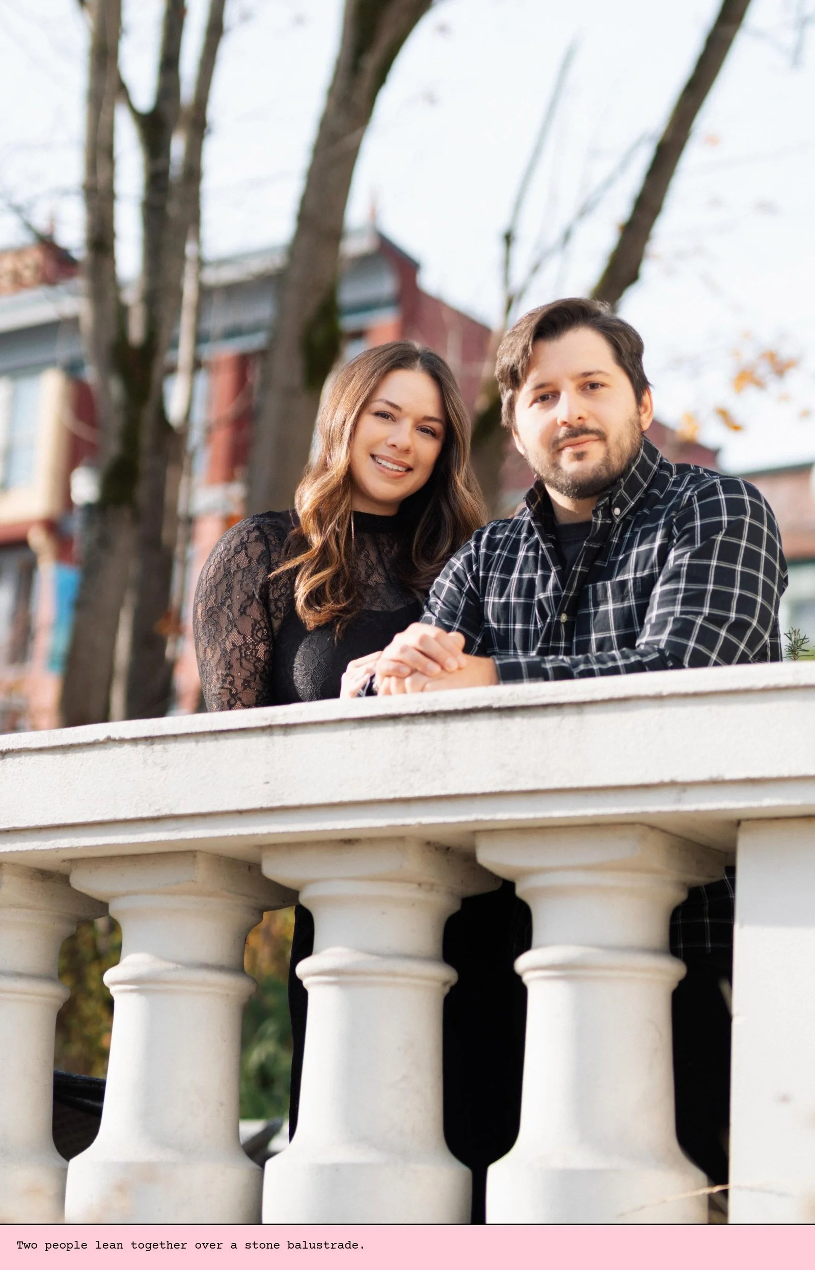 Two people lean together over a stone balustrade.