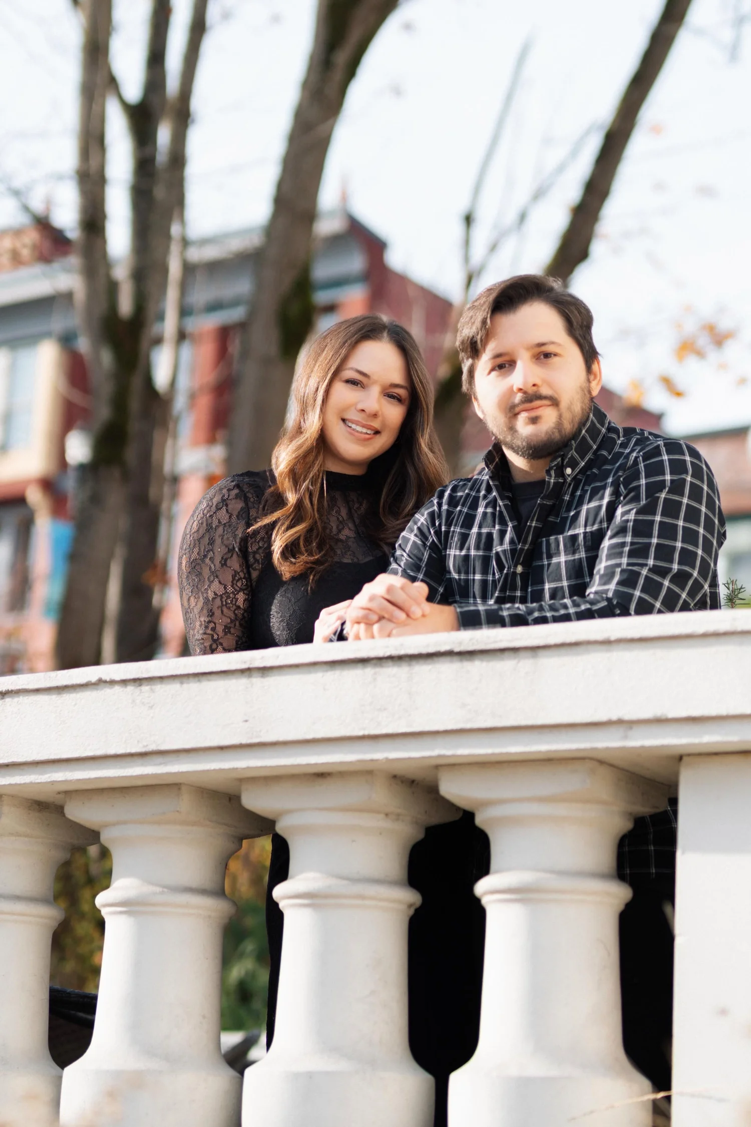 Two people lean together over a stone balustrade.