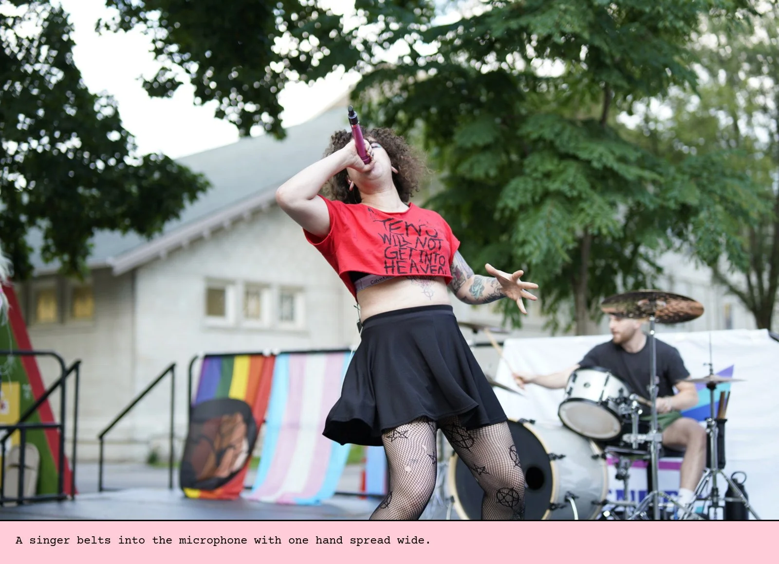A singer belts into the microphone with one hand spread wide.