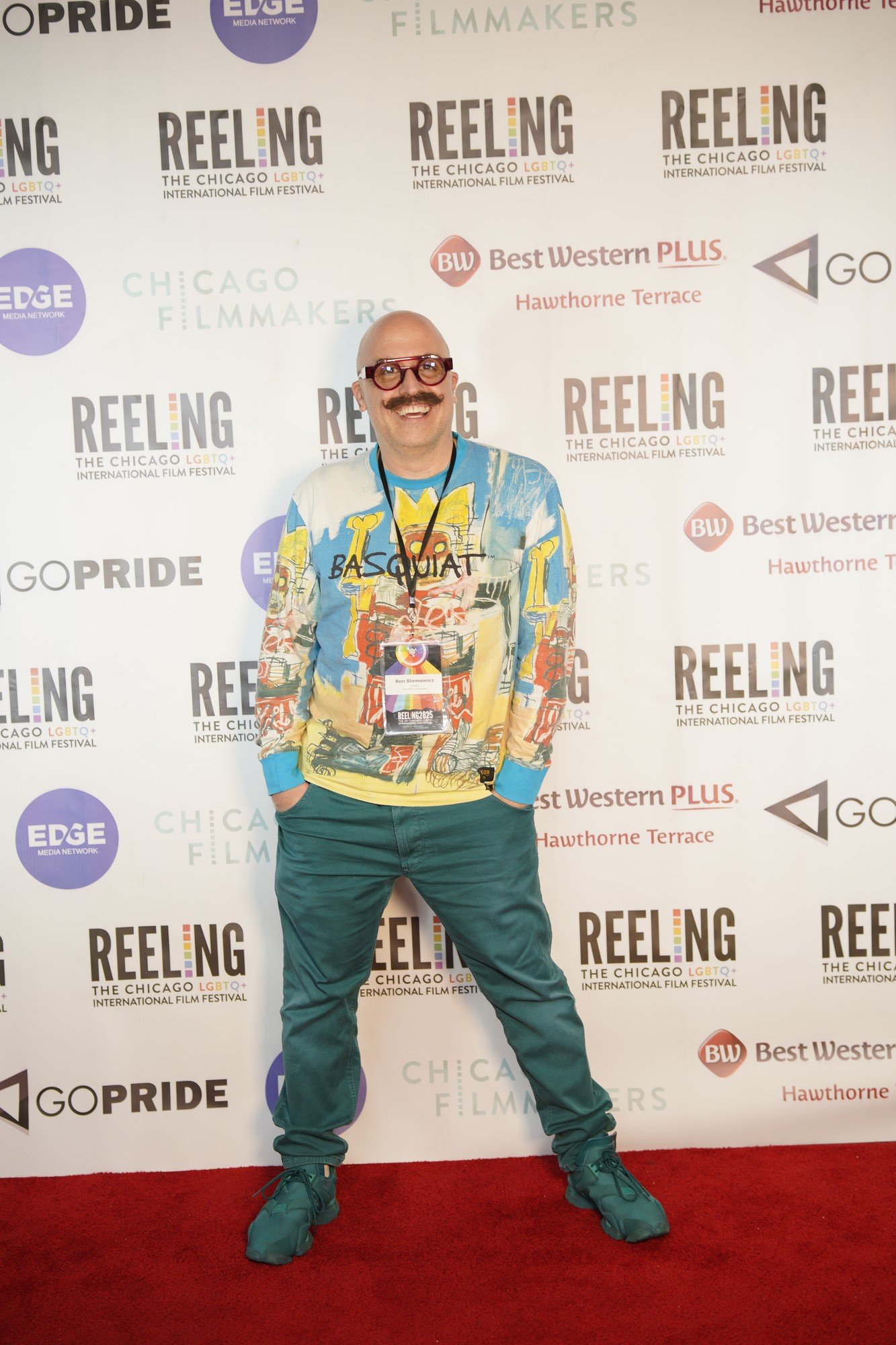 An attendee in a colorful shirt poses in front of the Reeling festival backdrop.