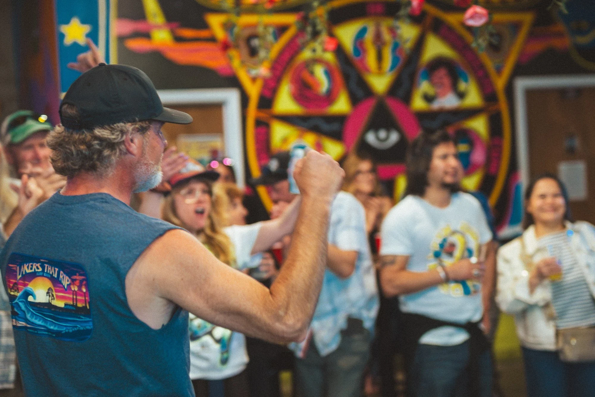 A vocalist faces an audience gathered closely in a room filled with colorful art.