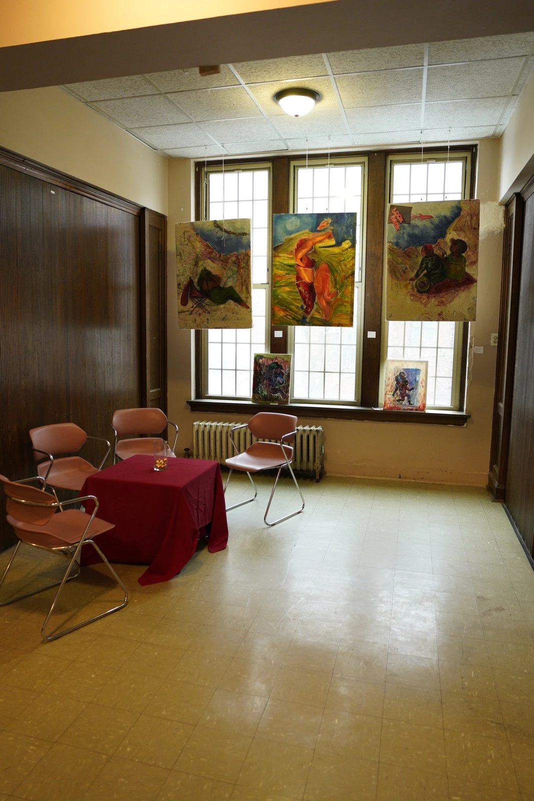 Small artworks hang in front of tall windows above tables in the event space.
