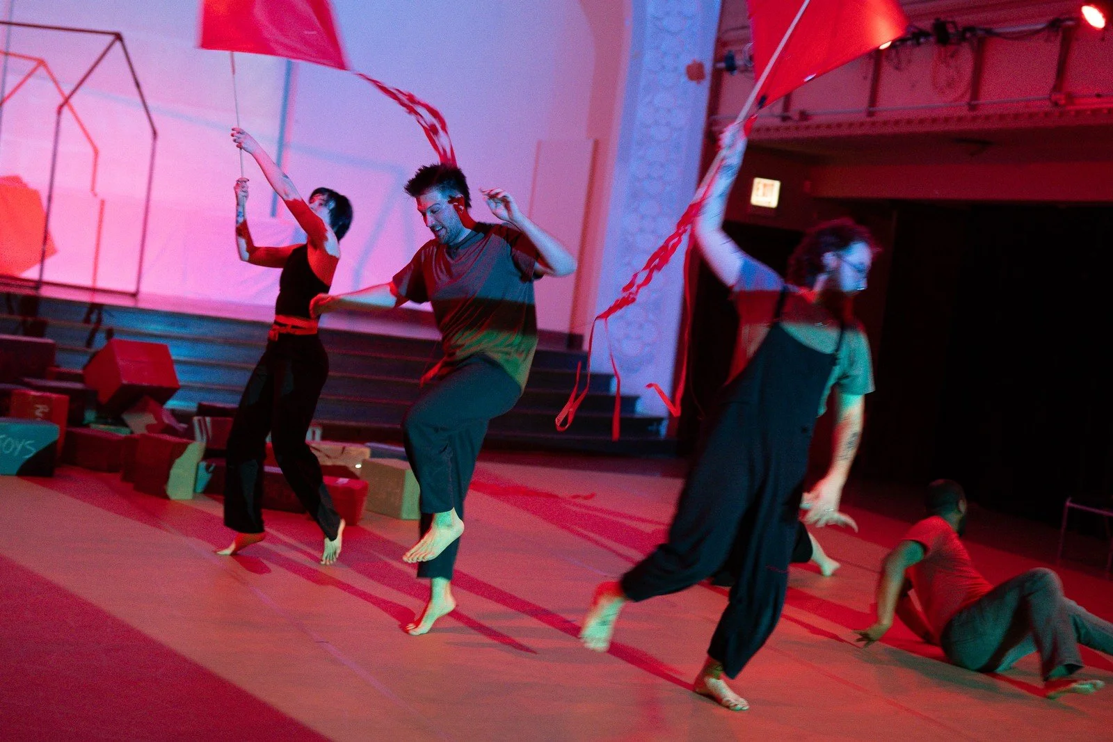 Performers leap while lifting red and white fabric through the air.