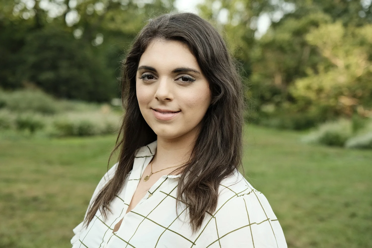 A checked white shirt sits against the soft green of the park.