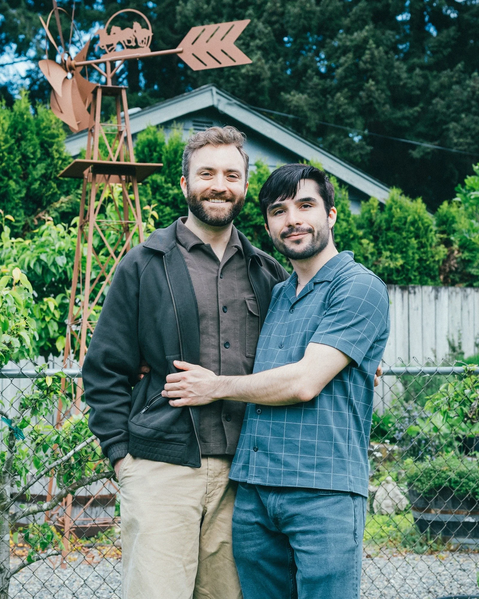 Two people embrace beside a garden fence.