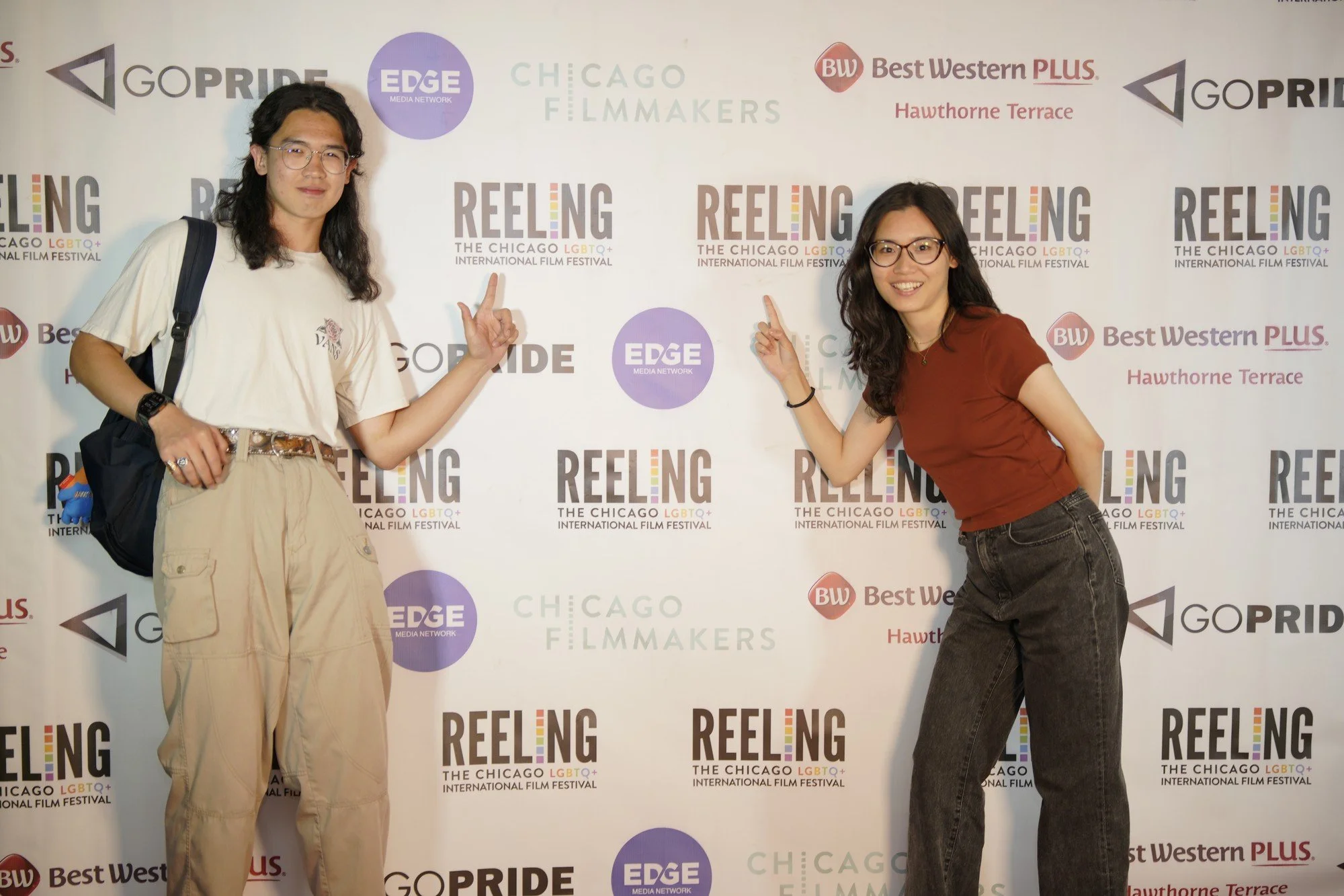 Two attendees pose together in front of the Reeling festival backdrop.