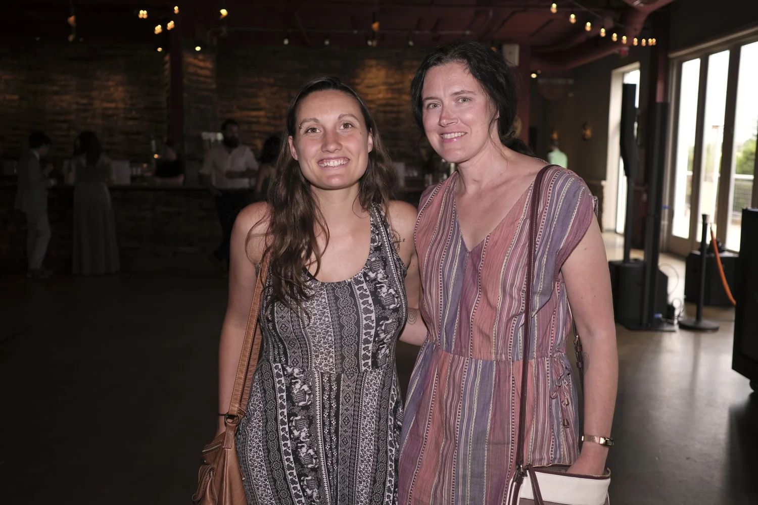Two guests stand together beneath the string lights.