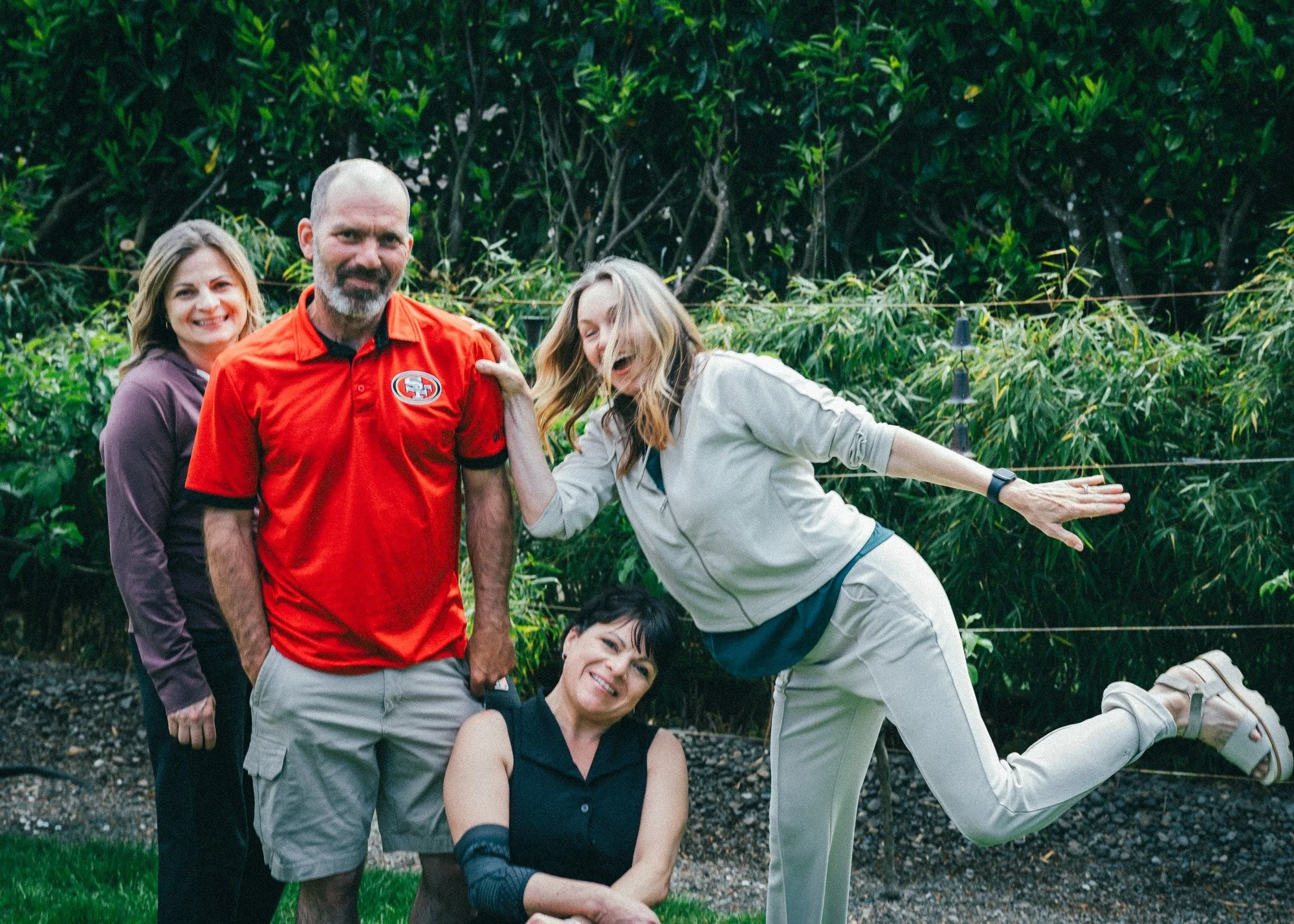 Four people strike playful poses outdoors.