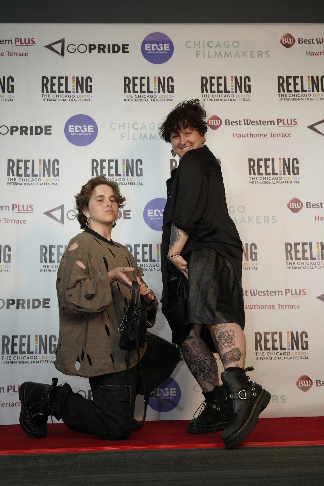 Two attendees pose playfully in front of the Reeling festival backdrop.