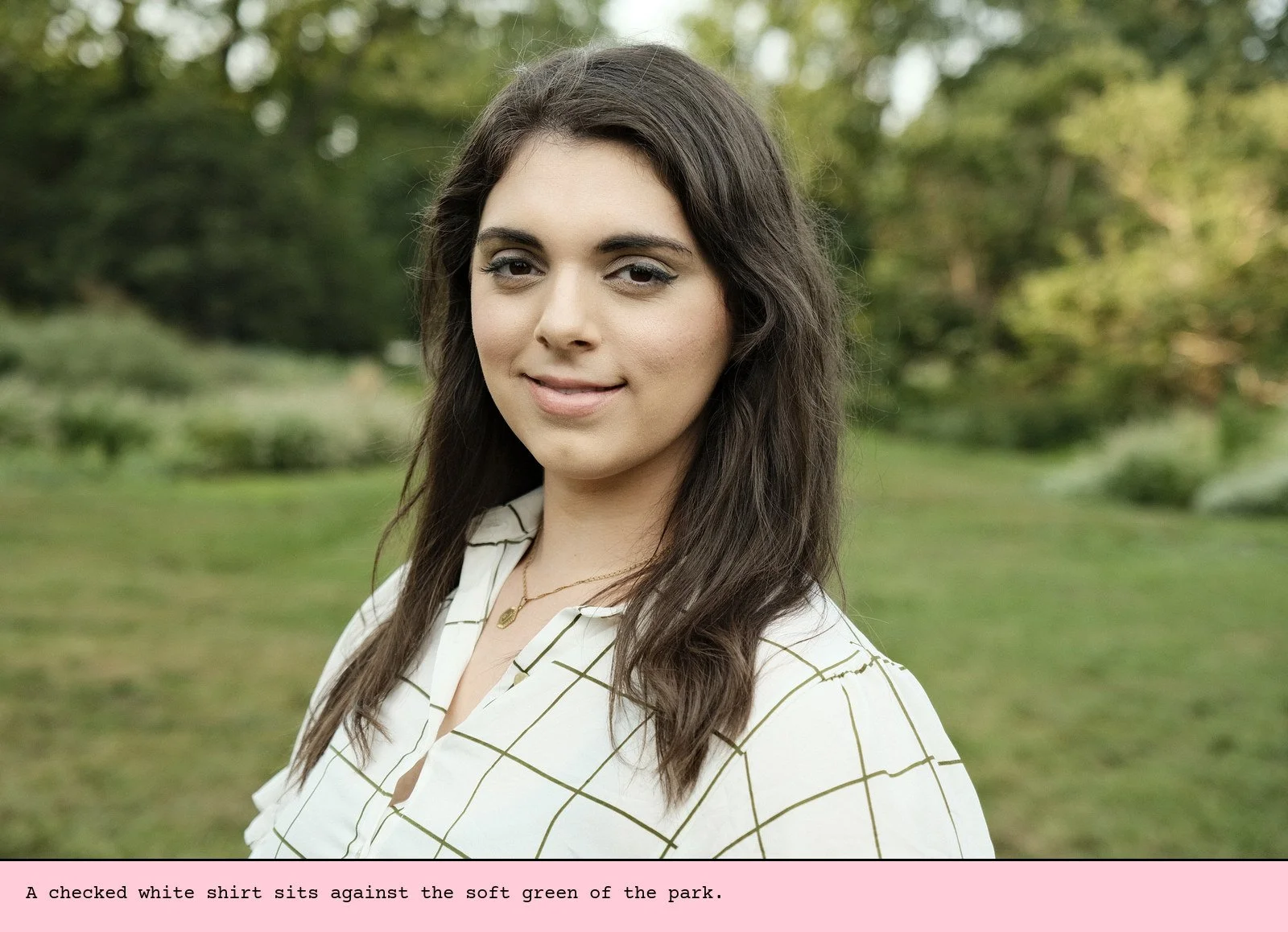 A checked white shirt sits against the soft green of the park.