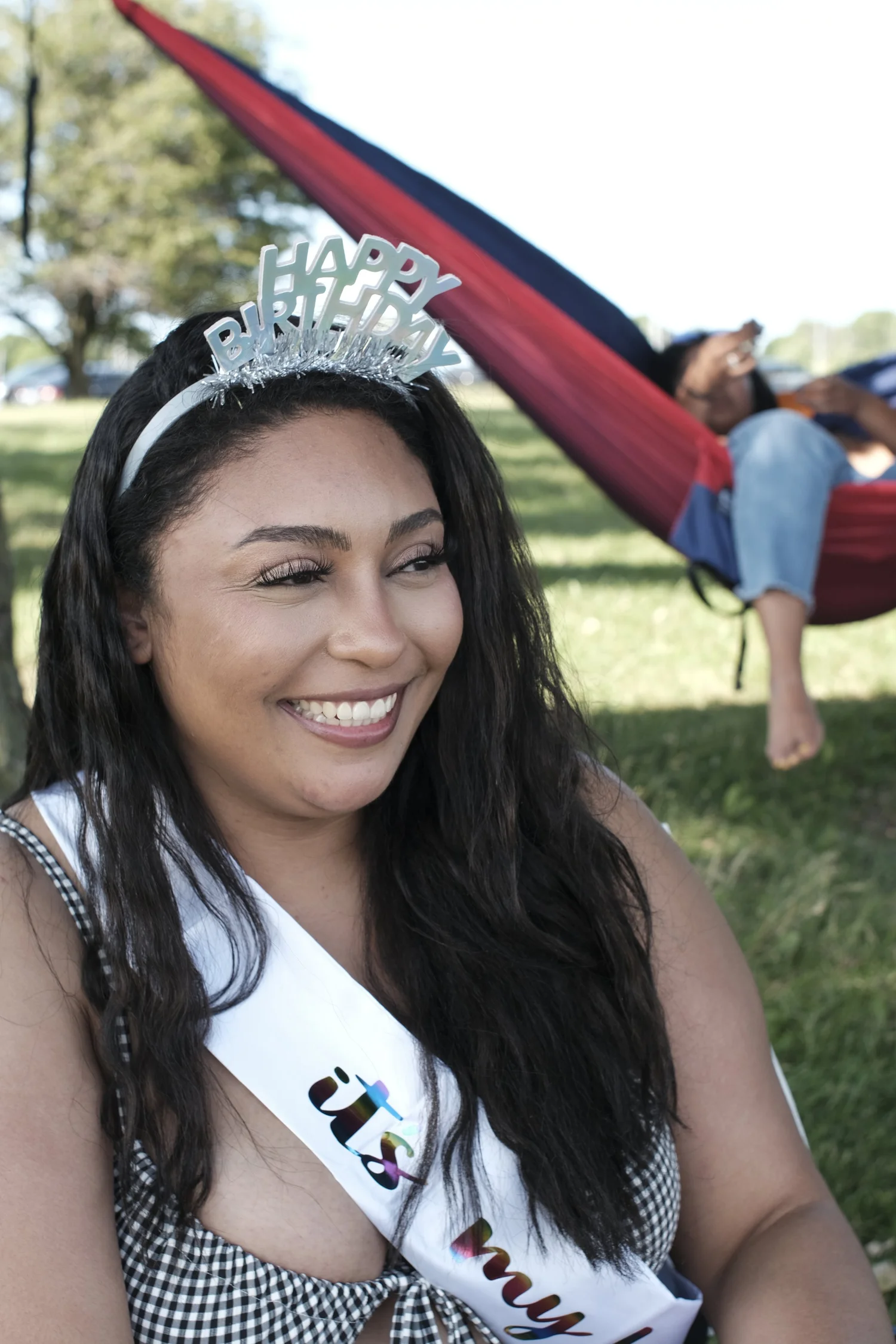 Smiling in a birthday headband beside the red hammock.