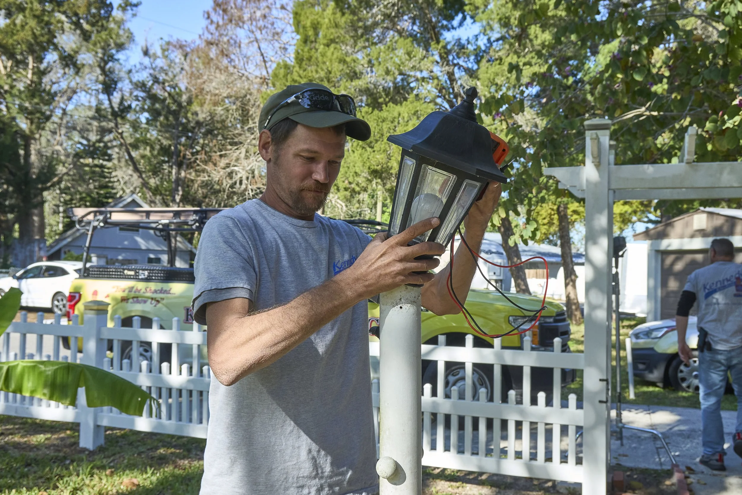 Man installing a black lantern/coach post light on a white column